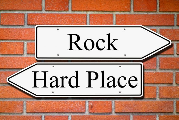 Between rock and hard place signpost concept brick wall