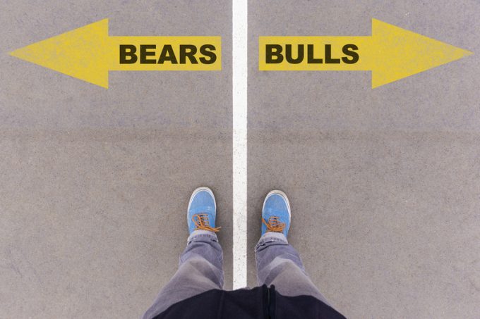 Bears vs Bulls text arrows on asphalt ground, feet and shoes on