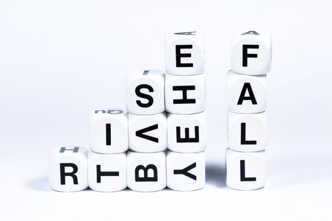 Lettered dice spelling out the words rise and fall on a white background