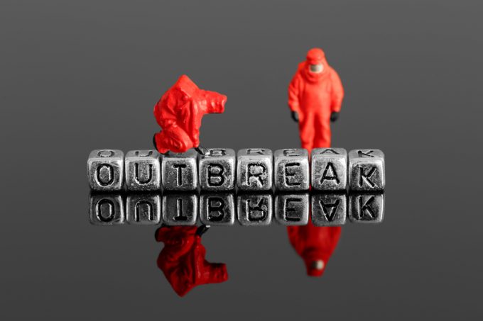 Miniature scale model team in chemical suits with the word outbreak on beads