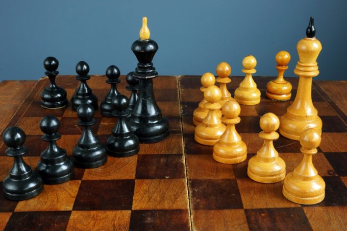 Leader vs boss or manager. Chess kings and pawns on desk.