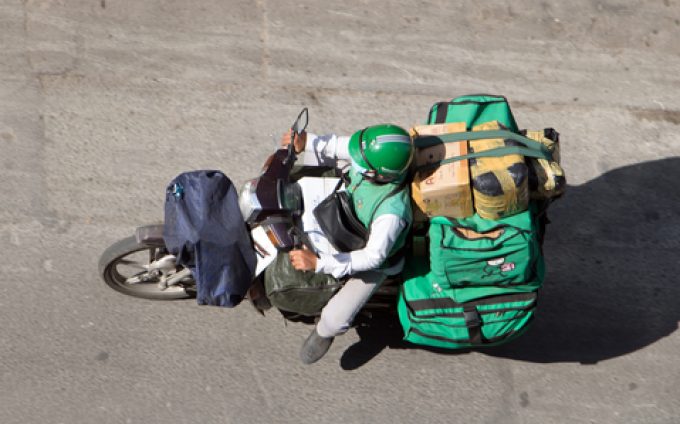 SAIGON, VIETNAM, DEC 18 2017.  Delivery of consignments on motorbike. Motorcyclist rides with delivery in the many green bags on street Saigon city, Vietnam.