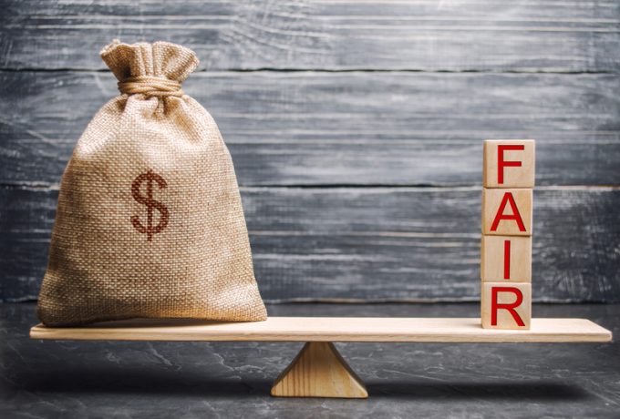 Money bag and wooden blocks with the word Fair. Balance. Fair value pricing, money debt. Fair deal. Reasonable price. Justified risk. Honest loan. Secured loans.