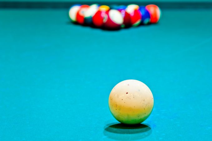 white cue ball close-up on a pool table covered with green baize