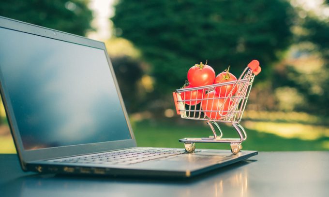 Concept of online grocery shopping. A miniature shopping cart wi