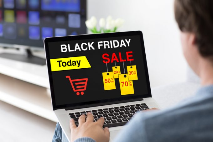 man typing on laptop keyboard with sale black friday screen
