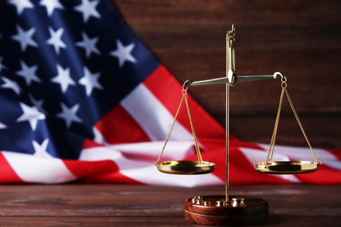 Scales of justice with american flag on brown wooden table