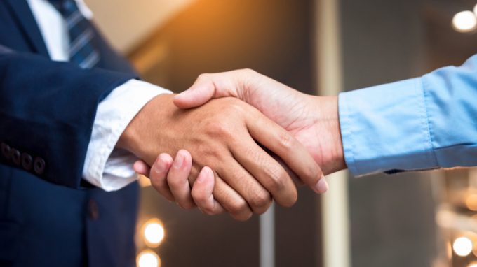 Close up businessmen shaking hands during a meeting. Handshake deal business corporate.