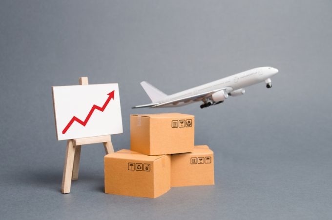 Airplane plane takes off behind stack of cardboard boxes and stand with red up arrow. concept of air cargo and parcels, airmail. Fast delivery of goods and products. Cargo aircraft. Logistics,