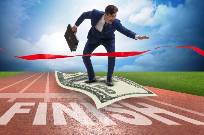 The businessman flying on dollar banknote towards finish line