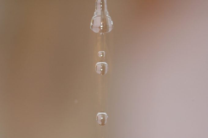 l falling water drop on beige background in close-up