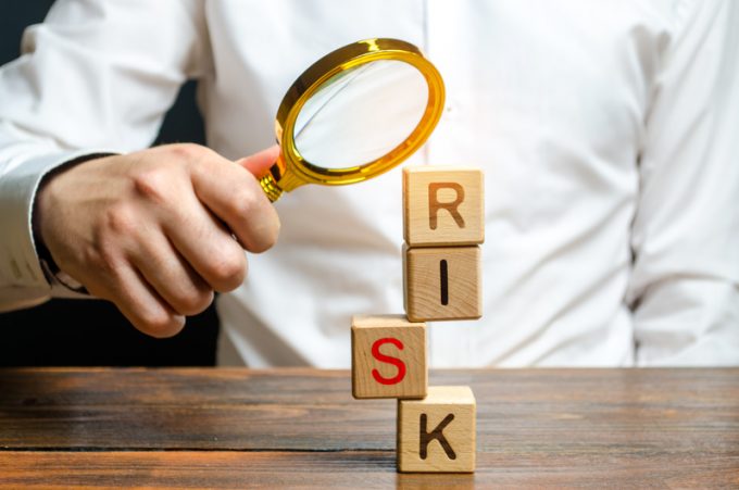 A man explores a tower of cubes with the word Risk. Search and correction of errors and failures. Risk management, cost assessment, and business and investment safety. Strengthen business resilience